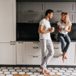 Kobieta i mężczyzna siedzący na blacie w białej kuchni z wzorzystą podłogą