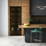 Drewniano-czarna kuchnia z zielonymi hokerami.